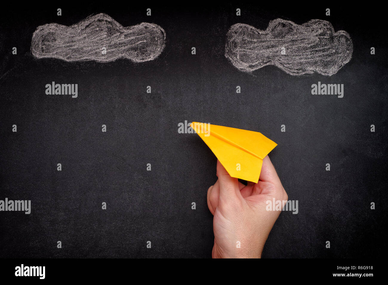 Hands holding yellow paper plane sous les nuages. Close up. Banque D'Images