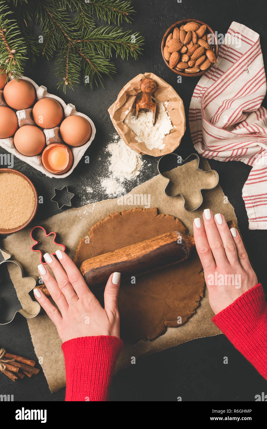 Rouler la pâte d'épices. Noël cuisson concept. Femme les mains avec rouleau à pâtisserie pour préparer la pâte. Vue d'en haut Banque D'Images