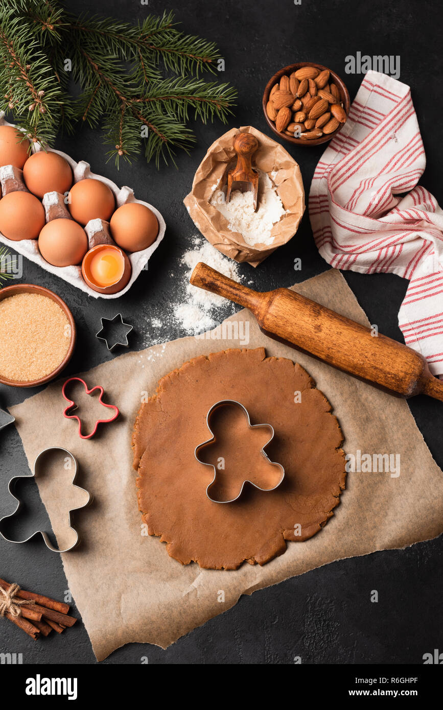 Gingerbread cookies préparation. Cookie dough, emporte-pièce, les ingrédients sur fond noir. Vue d'en haut Banque D'Images