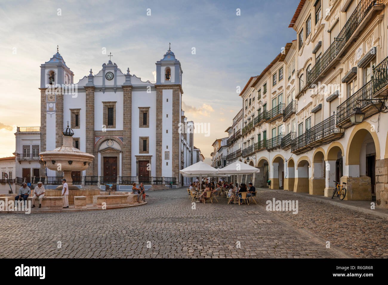 Praca do Giraldo et l'Igreja de Santo Antao avec les bâtiments historiques et les cafés autour de la place au coucher du soleil, Evora, Alentejo, Portugal, Europe Banque D'Images