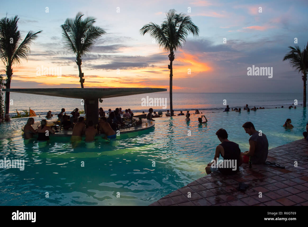 Les touristes profiter d'un Bali de la piscine pendant le coucher du soleil Banque D'Images