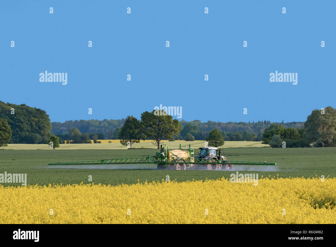 Agriculteur dans le tracteur l'épandage d'herbicides / insecticides / pesticides sur terrain avec pulvérisateur traîné au printemps Banque D'Images