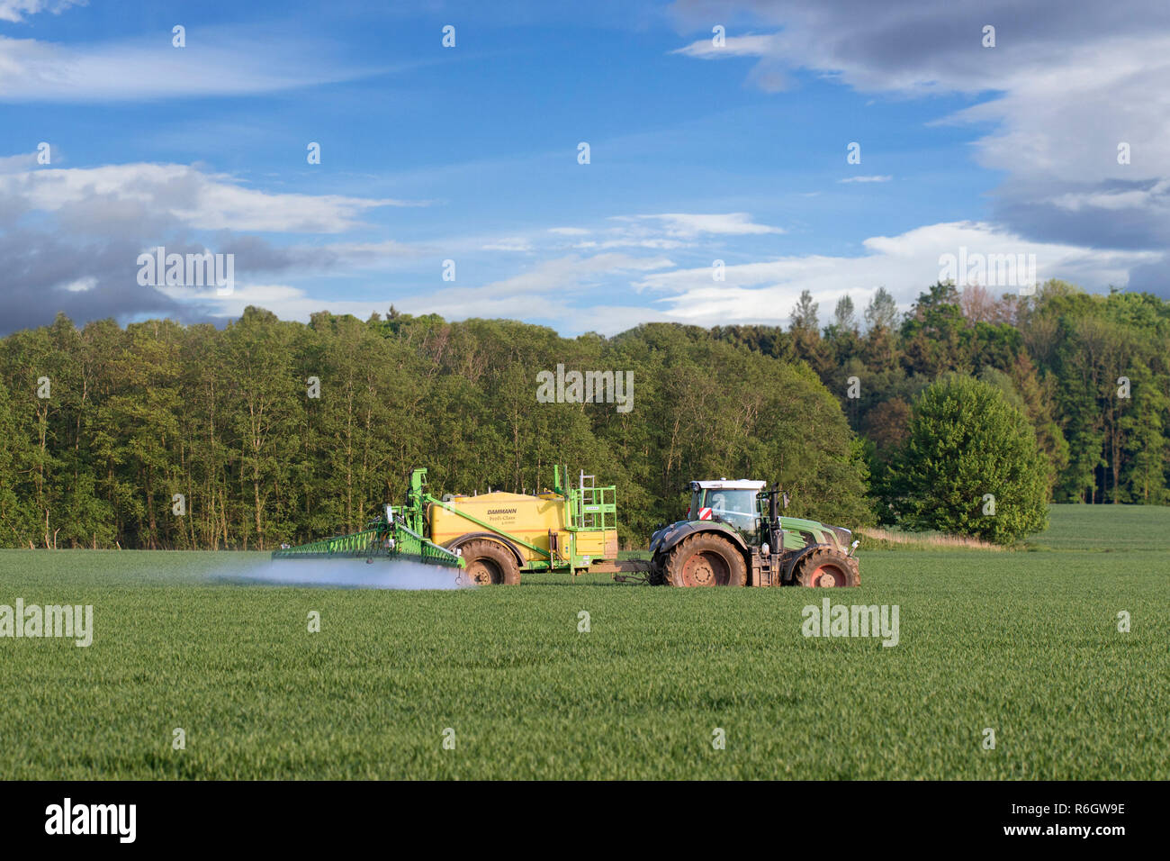 Agriculteur dans le tracteur l'épandage d'herbicides / insecticides / pesticides sur terrain avec pulvérisateur traîné au printemps Banque D'Images