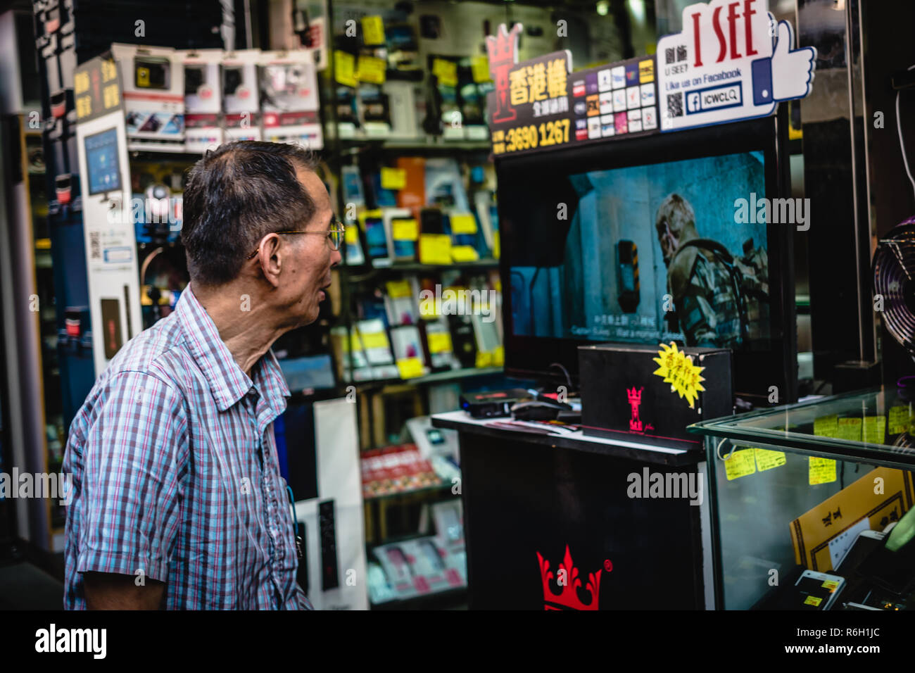 Un vieil homme regarde un plat à un marché de rue à Hong Kong Banque D'Images