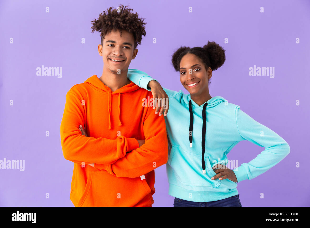 Photo de teen african american couple dans des vêtements colorés smiling while Standing together sur fond violet isolés Banque D'Images