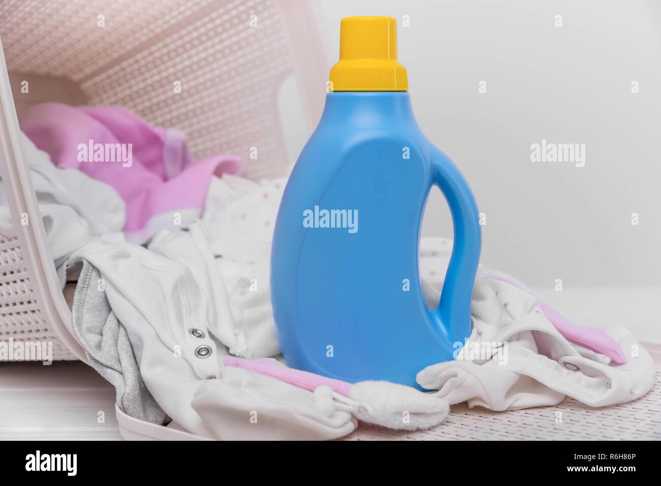 Bouteille de lessive dans le panier avec des vêtements de bébé. Banque D'Images