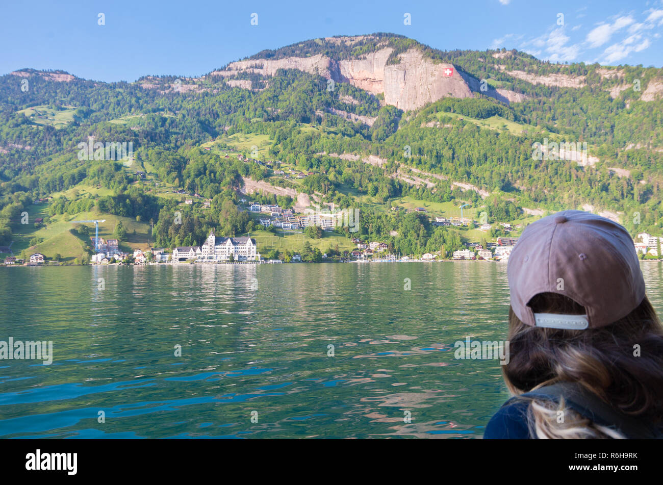 Belle jeune femme sur un lac dans les alpes suisses à partir d'un bateau avec la ville de Vitznau dans l'arrière-plan Banque D'Images