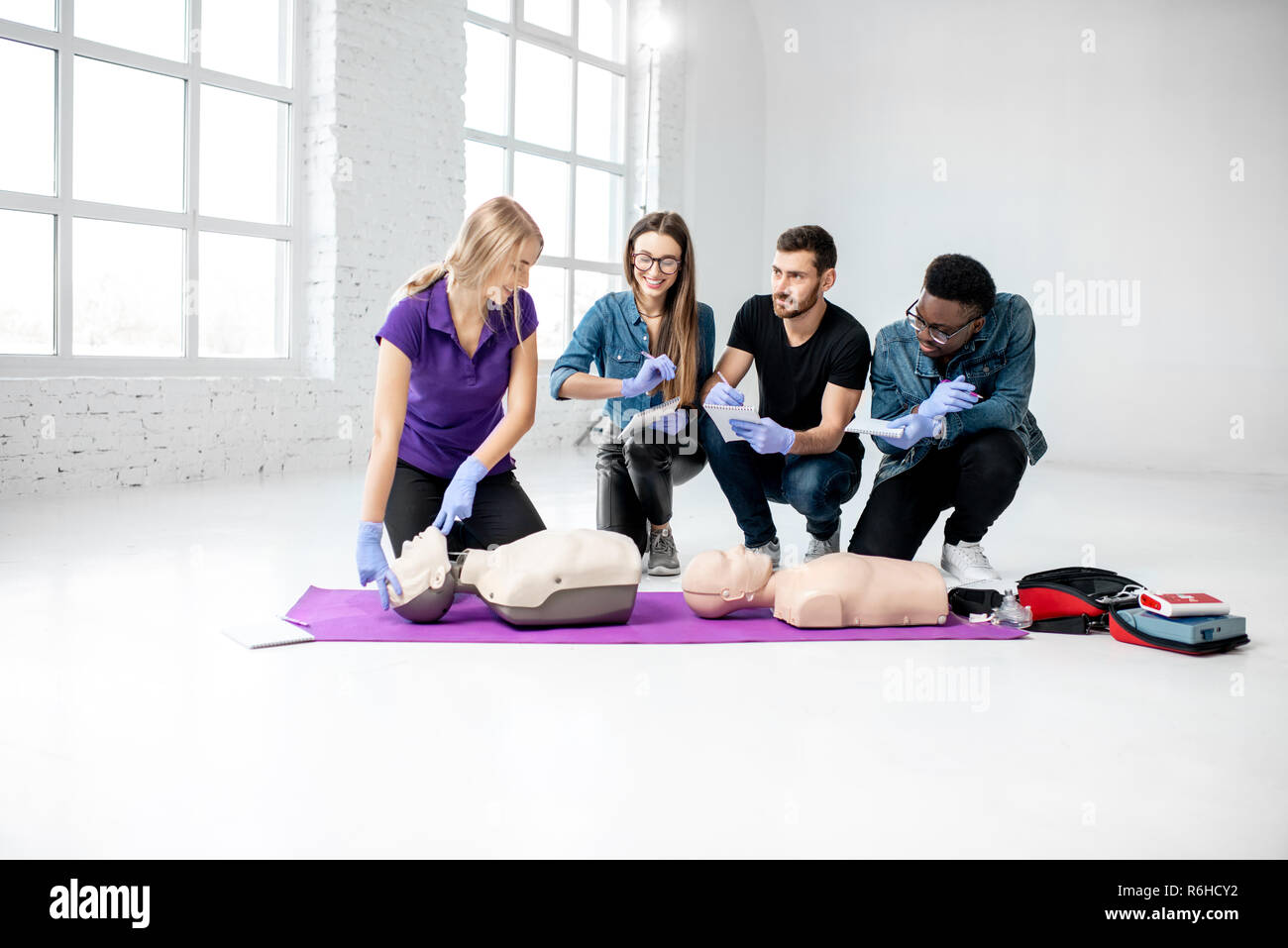 Groupe de jeunes d'apprendre à faire de la respiration artificielle avec des nuls au cours de la formation aux premiers secours dans la chambre blanche Banque D'Images