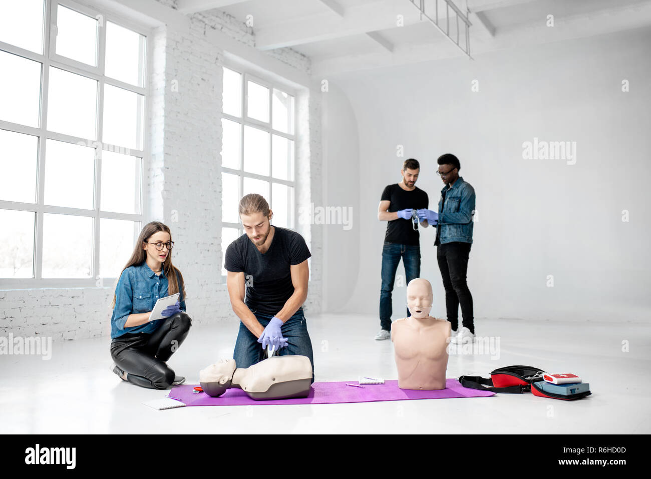 Groupe de jeunes de faire pratiquer la respiration artificielle avec des nuls au cours de la formation aux premiers secours dans la chambre blanche Banque D'Images