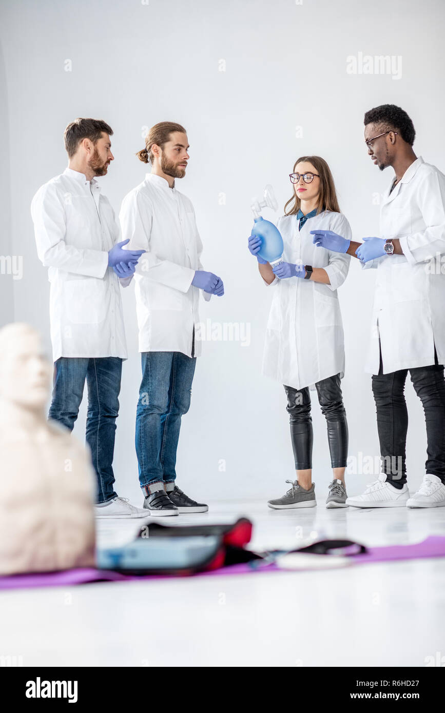 Groupe de jeunes membres du comité permanent et de parler ensemble pendant la pause de la formation en premiers soins médicaux avec les bébés et sucettes sur le plancher Banque D'Images