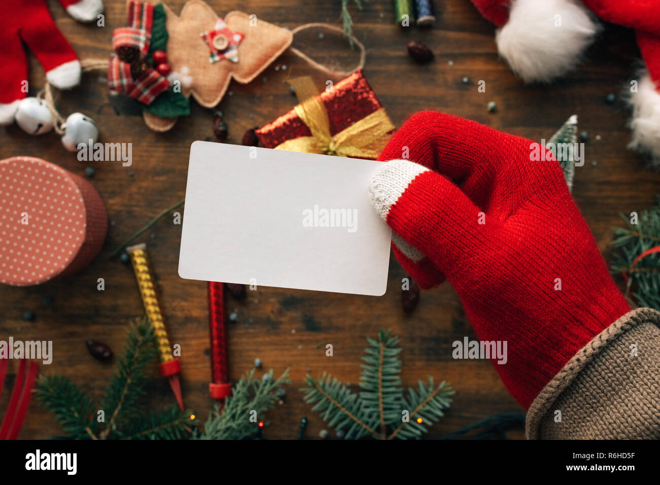 Carte de Noël maquette détenus par la main sur table avec diverses décorations de vacances Banque D'Images