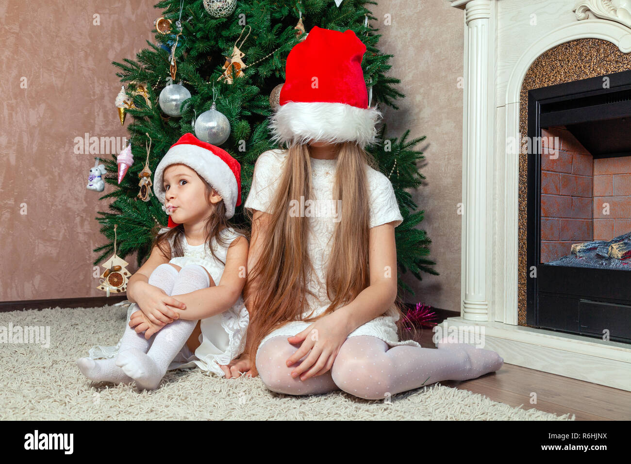 Deux copines sont à poser et faire le Nouvel An des arbres près de la cheminée dans un luxueux hôtel particulier de pays. concept de l'enfance insouciante et g Banque D'Images