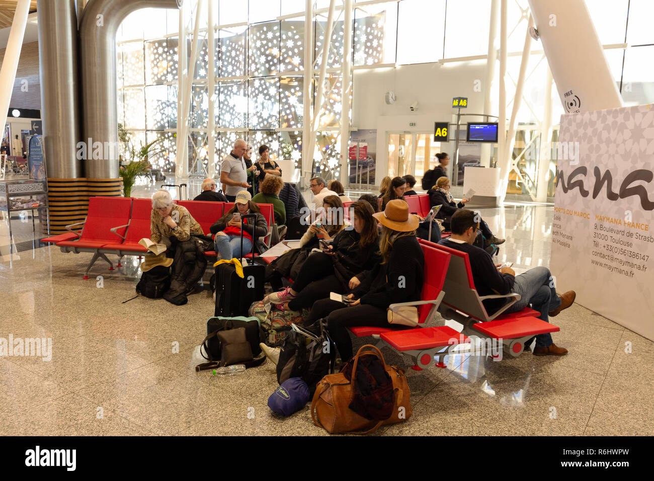 Les départs de l'aéroport de Marrakech, - des gens assis en attente à l'entrée, salle d'embarquement, l'aéroport de Marrakech, Maroc Afrique du Nord Banque D'Images