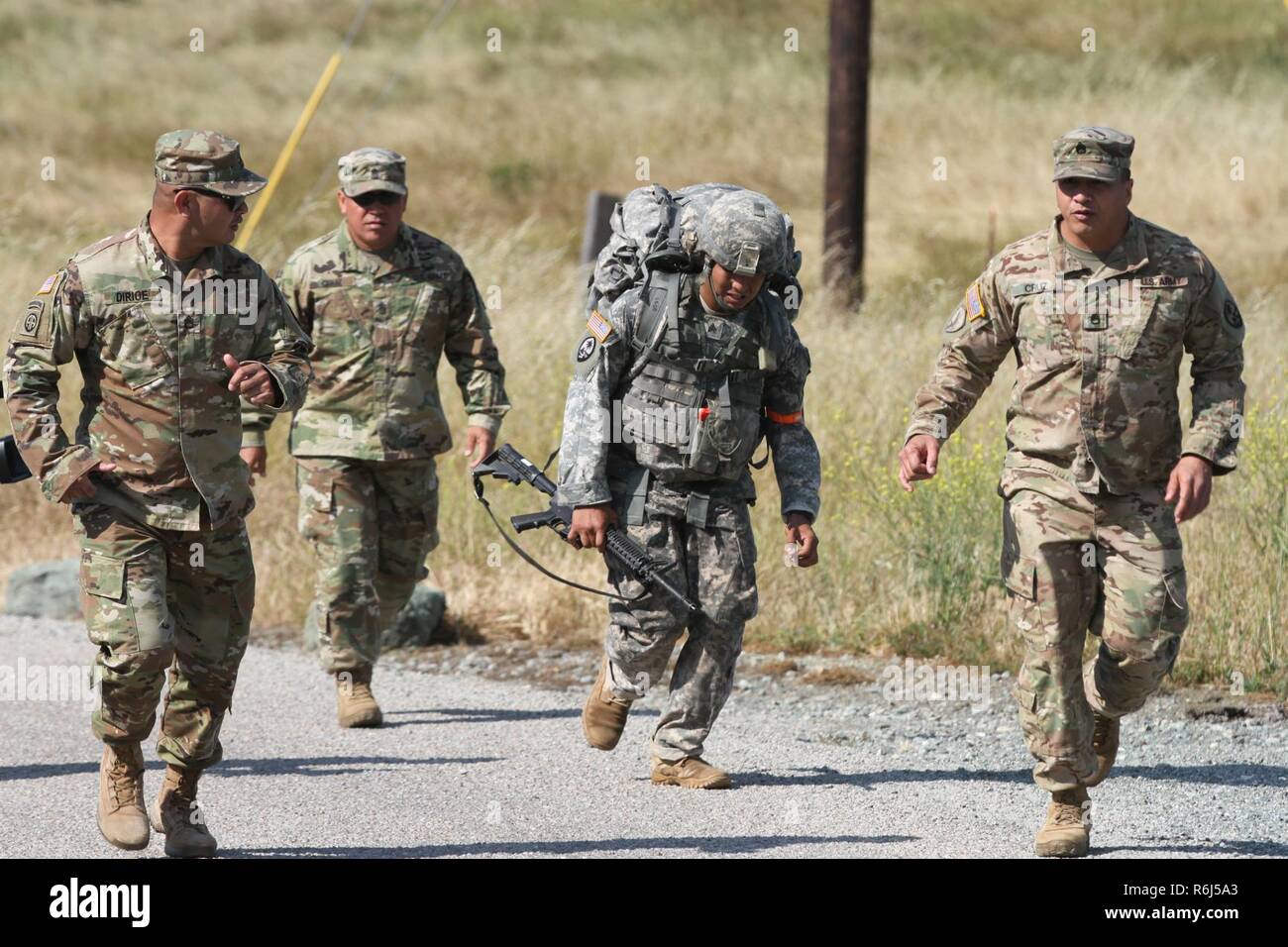 Le Sgt. Jacob T. Penaflor, centre, de l'Army National Guard, reçoit les encouragements de Sgt. 1re classe Kevin Dirige, commande le Sgt. Le Major Ken Cruz et le sergent. Dino Cruz comme Penaflor arrive à la fin de l'épuisant 12-mile ruck sack mars mai 18 au cours de la Garde nationale 2017 Région Bureau VII CONCOURS Meilleur guerrier 17 mai à San Luis Obispo, Californie. Les concurrents avaient à transporter un 35 livres de matériel tout au long de la région vallonnée, isolée bien sûr. Banque D'Images