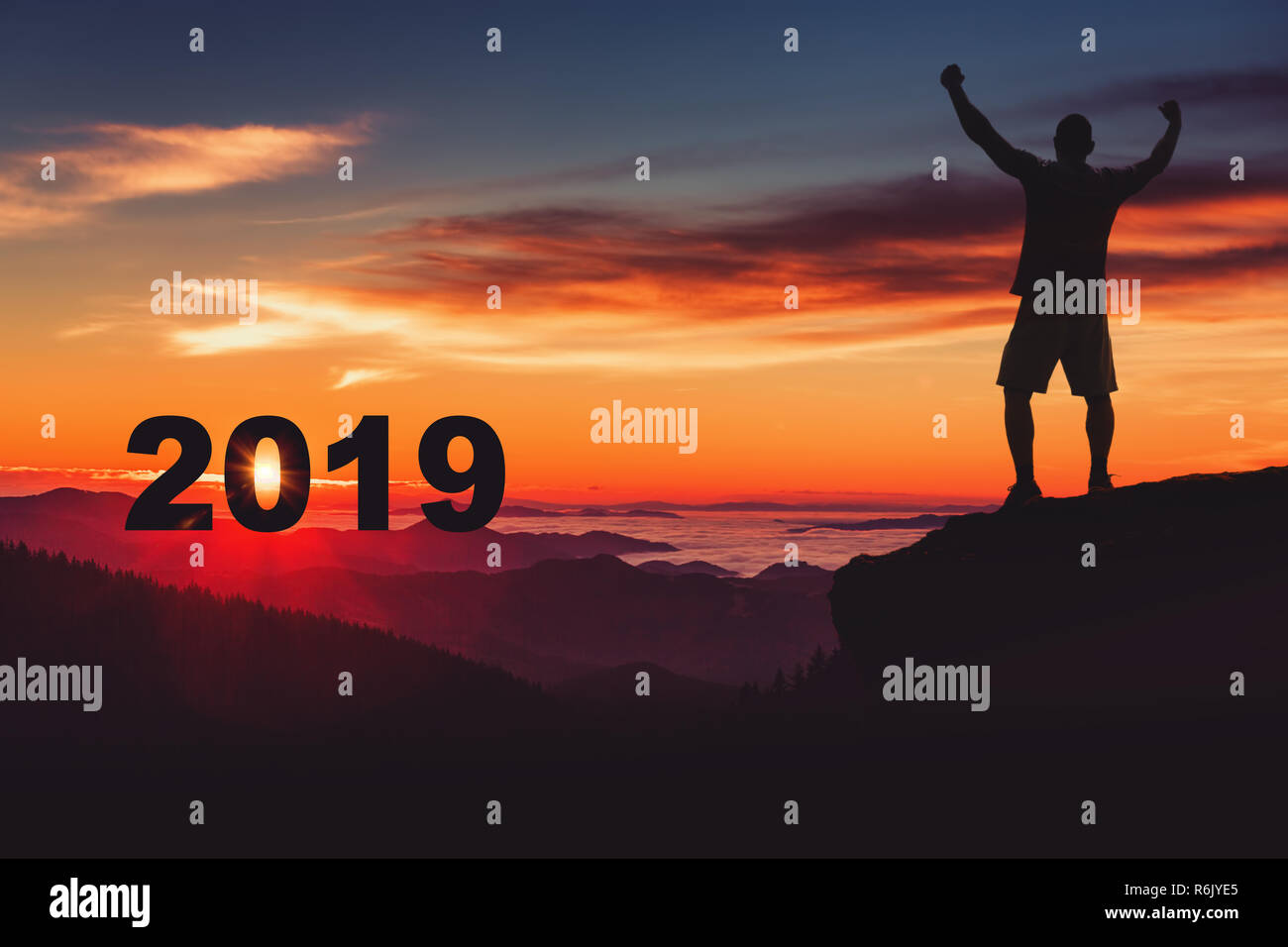 L'homme silhouette sur le sommet de la montagne en regardant le lever du soleil et 2019 ans alors qu'il célèbre. Banque D'Images
