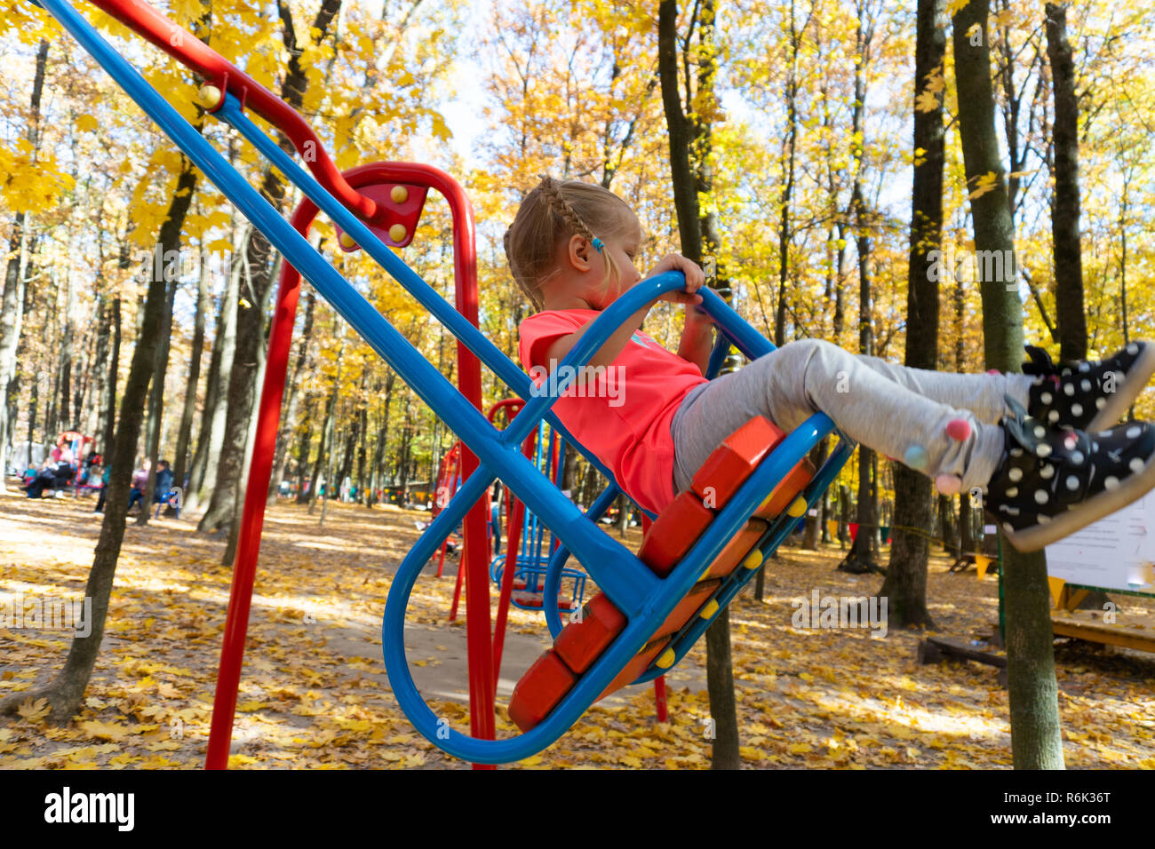 Fille se balançant sur swing en parc pour enfants Banque D'Images