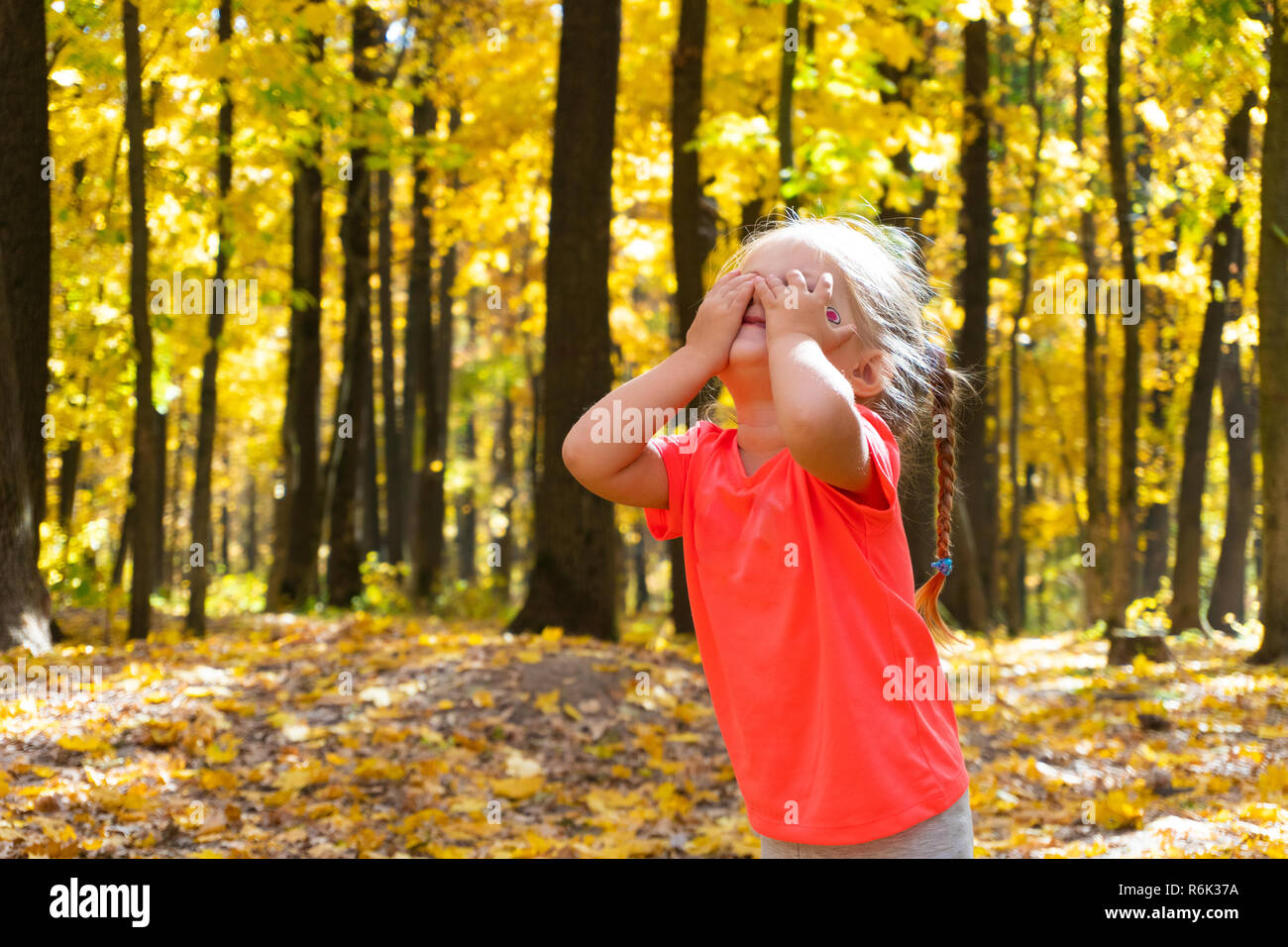 Girl joue à cache-cache dans le parc en automne Banque D'Images