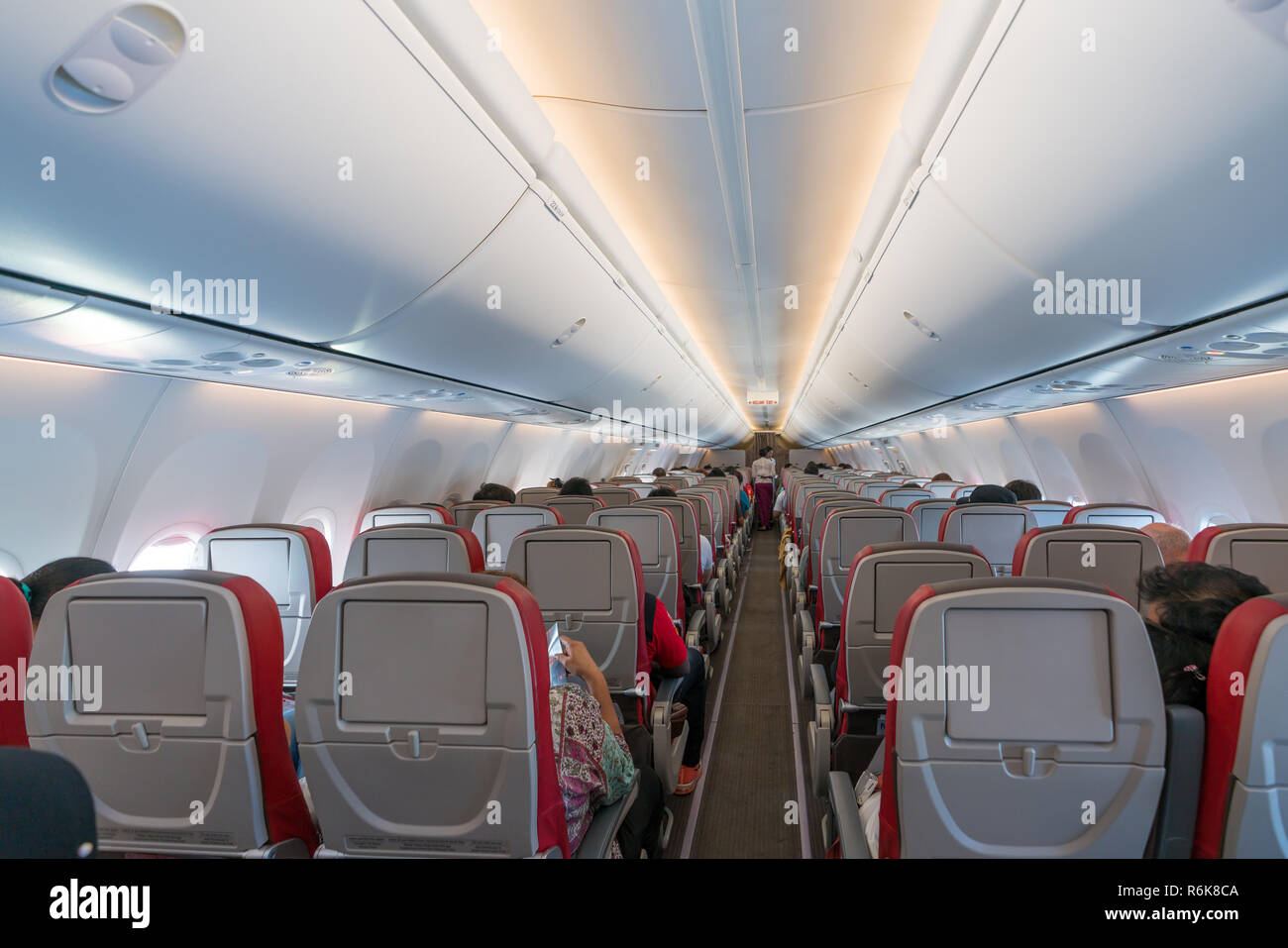 Intérieur de l'avion avec les passagers des sièges et hôtesse en uniforme autour de l'allée. Banque D'Images