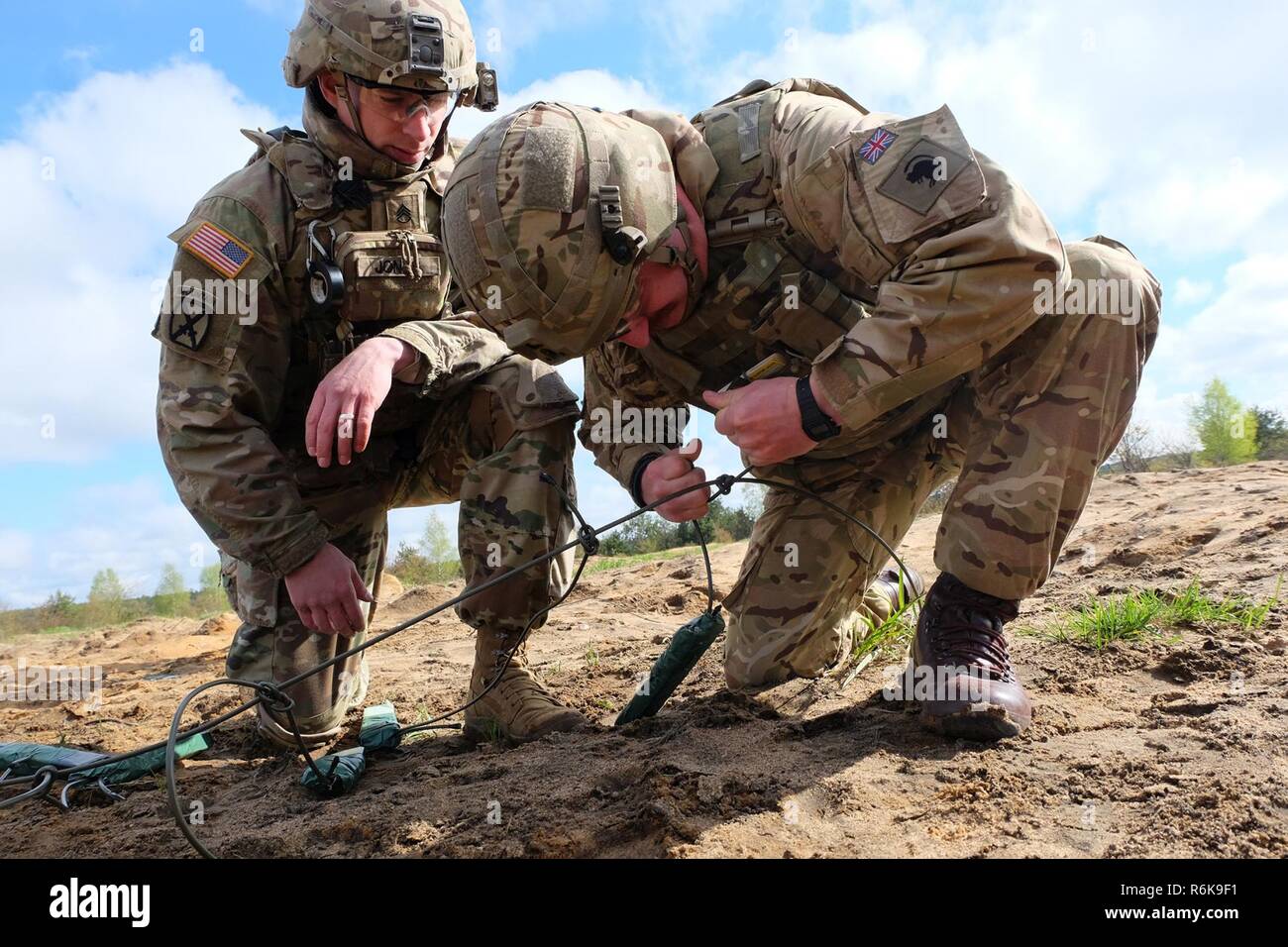 Pologne Groupe bataille soldat SSG. Brice Jones supervise les Mustang Cpl. James Ahara alors qu'il resserre sa charge explosive à la confiance d'un tir réel au cours de la formation de démolition près de Bemowo Piskie Domaine de formation, la Pologne, le 10 mai. L'interopérabilité formation a aidé les États-Unis et le Royaume-Uni l'ingénierie groupe de combat des soldats effectuent des missions de démolition dans un environnement mixte. Banque D'Images