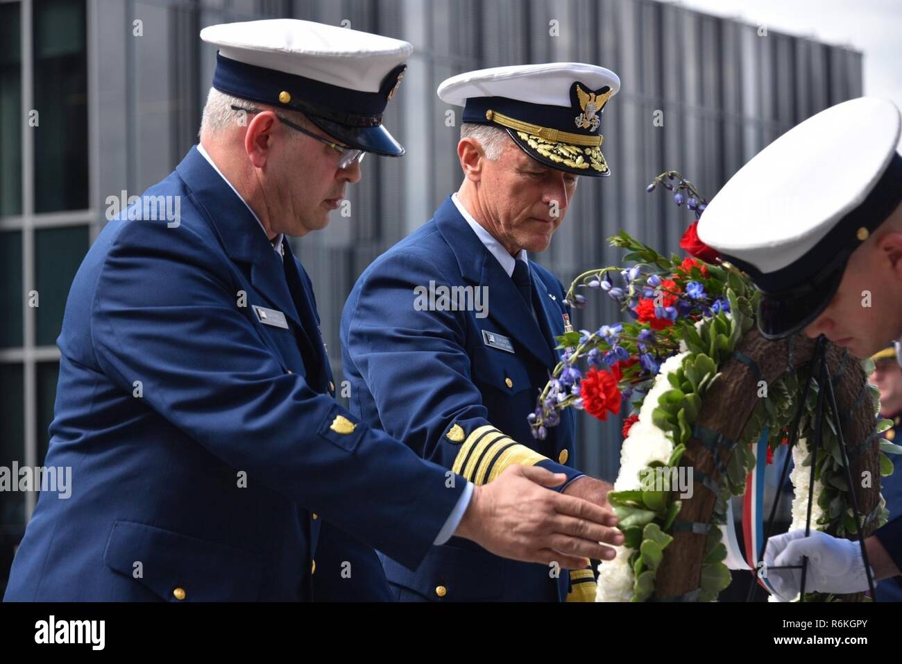 Master Chief Petty Officer de la Garde côtière et de la Garde côtière Steven Cantrell Commandant Adm. Paul Zukunft une couronne en face d'une photo du garde-côte de Tampa et de l'équipage au cours d'une célébration de la Journée du souvenir à la Douglas A. Munro du bâtiment du siège de la Garde côtière canadienne à Washington, D.C., le 26 mai 2017. La Faucheuse Tampa a été torpillé après avoir escorté un convoi de Galles en 1918, entraînant la perte de toutes les 131 personnes à bord. La Garde côtière américaine Banque D'Images