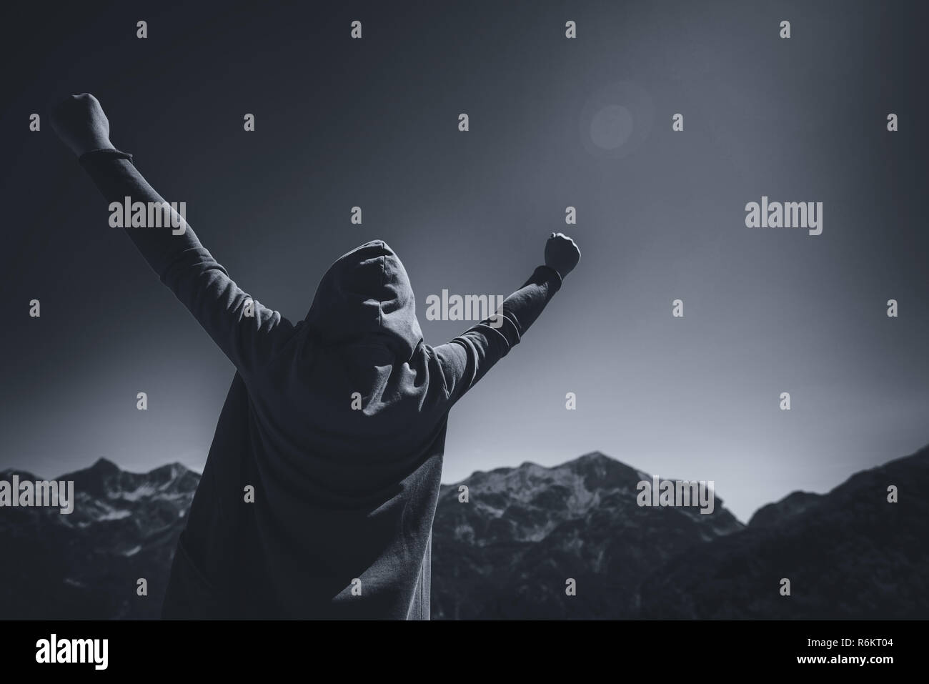 Heureux et satisfaits female traveler avec mains soulevées dans victorious V poser debout au sommet de la montagne et à la recherche à l'horizon Banque D'Images