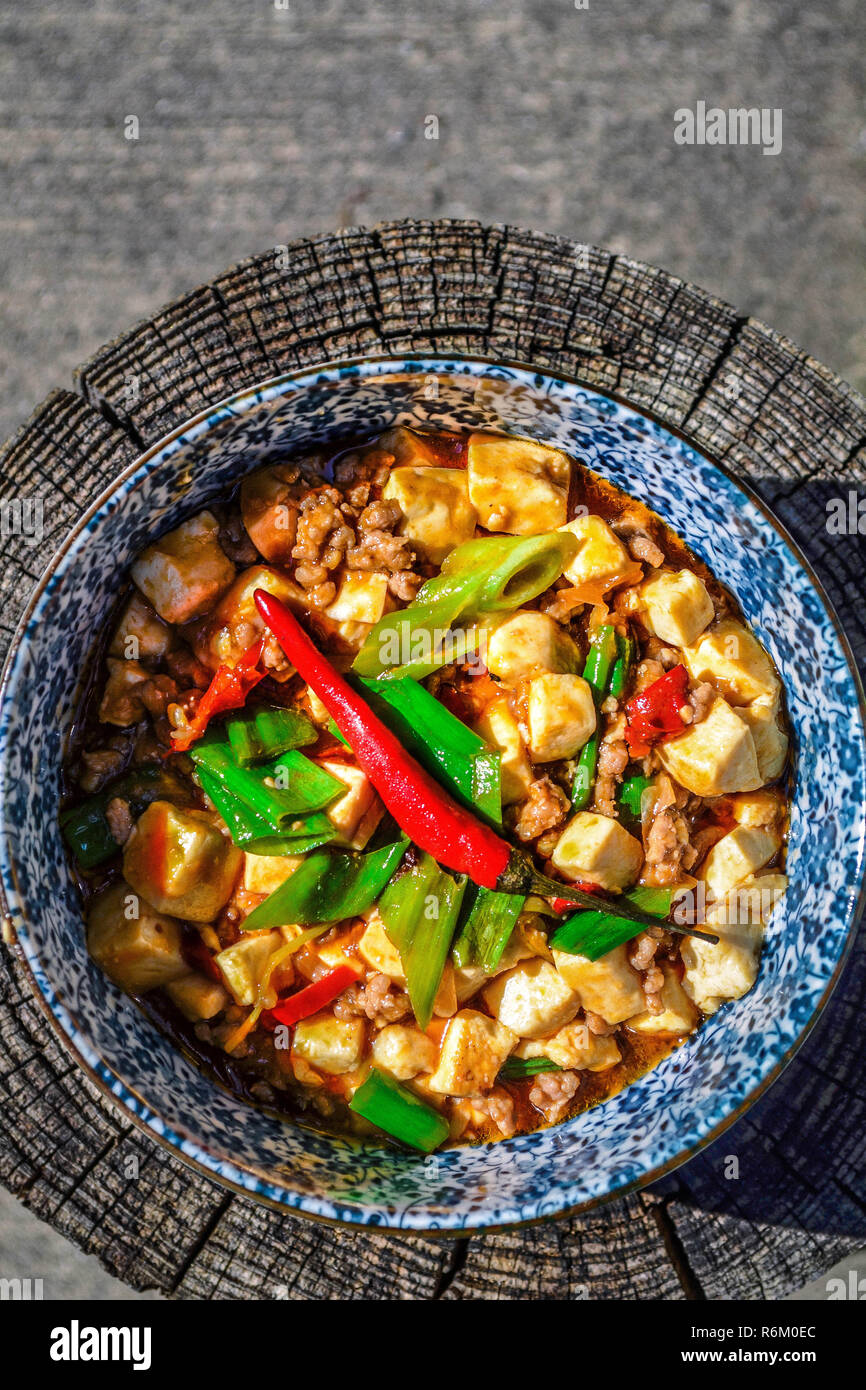 Le Mapo Tofu - le tofu, le porc et les légumes dans une sauce sauce chinoise, frais généraux indiqués dans un bol sur une surface en bois Banque D'Images