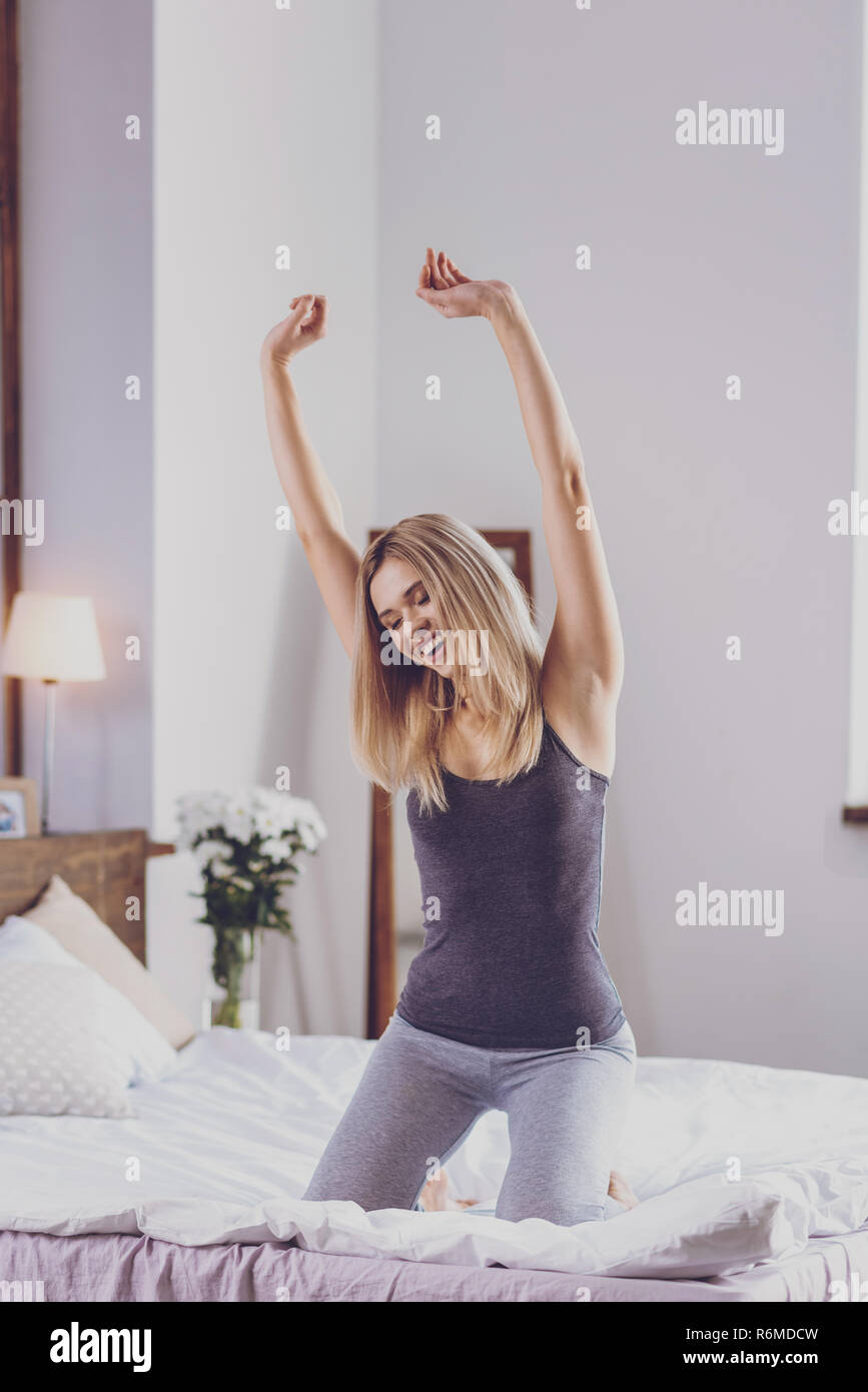Jeune femme optimiste faisant matin stretching on bed Banque D'Images