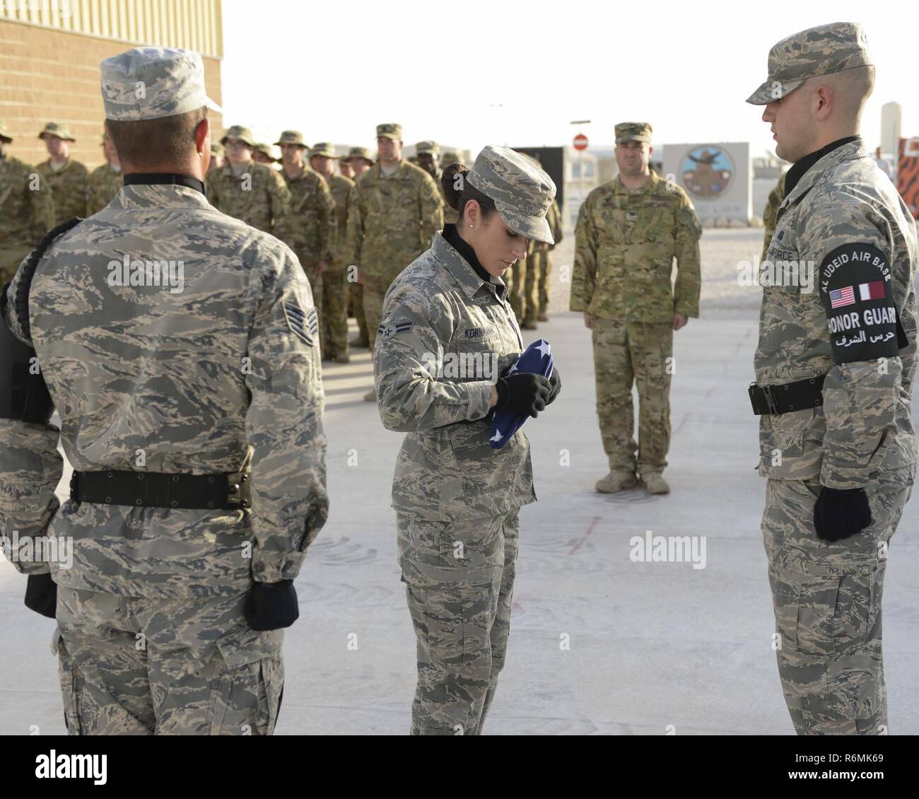 Les aviateurs de l'US Air Force 1re classe Jessica Kornmann, 379e Escadre expéditionnaire de la garde d'honneur, plie le drapeau américain tandis que d'autres membres de la garde d'honneur ainsi que des membres d'Al Udeid Air Base stand dans salut en Al Udeid Air Base, au Qatar, le 29 mai 2017. Le drapeau la retraite était partie d'une journée de réflexion tenue cérémonie commémorative en l'honneur de ceux qui sont morts en service militaire. Banque D'Images