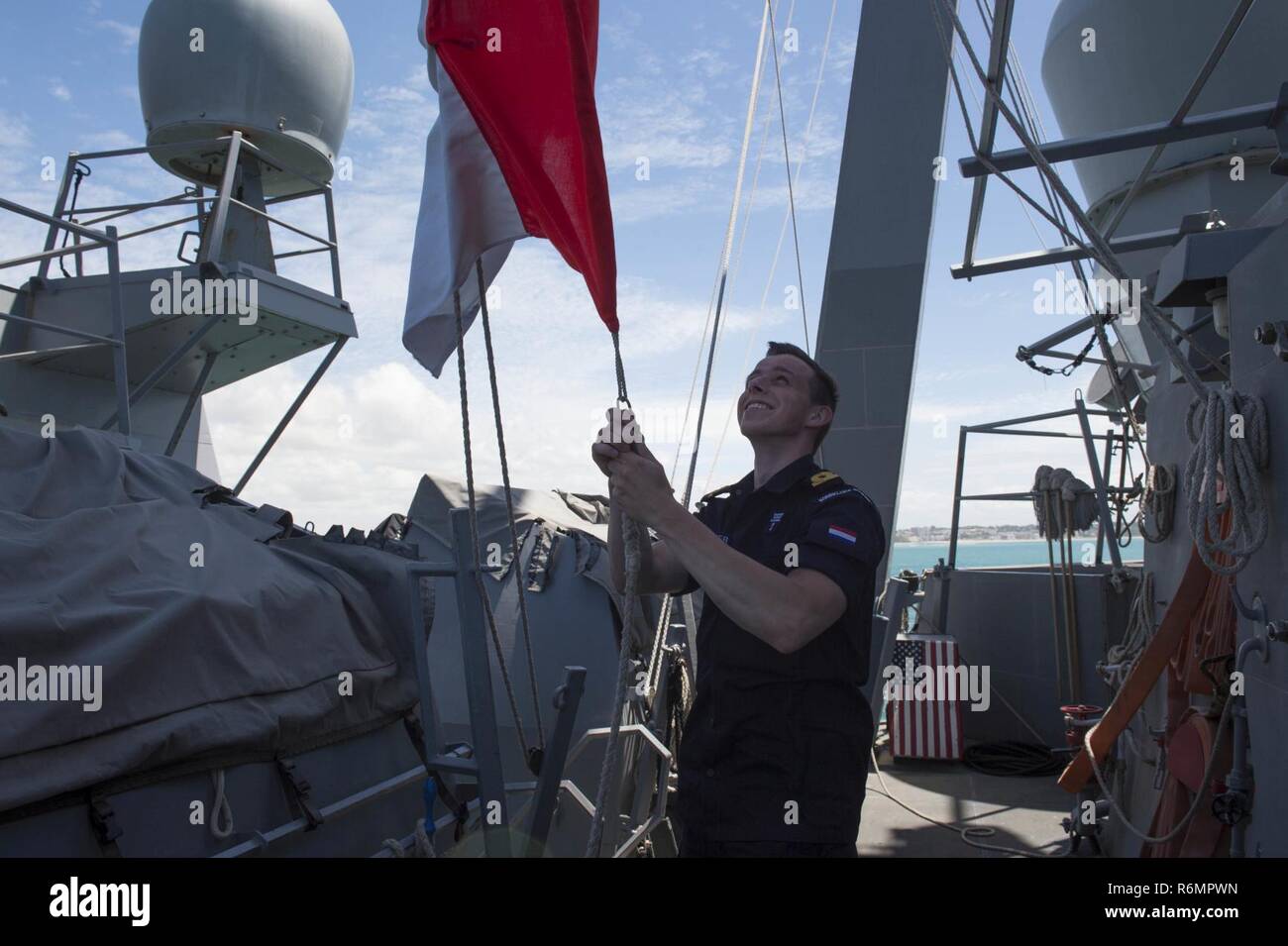La station navale de Rota, Espagne (29 mai 2017) - Marine royale néerlandaise Ensign Maarten Burger fait tomber un drapeau à bord de la classe Arleigh Burke destroyer lance-missiles USS Carney (DDG 64) alors que la base navale de Rota au départ, l'Espagne, le 29 mai 2017. Carney, l'avant-déployé à Rota, effectue actuellement sa troisième patrouille dans la sixième flotte américaine zone d'opérations à l'appui de la sécurité nationale des États-Unis en Europe. Banque D'Images