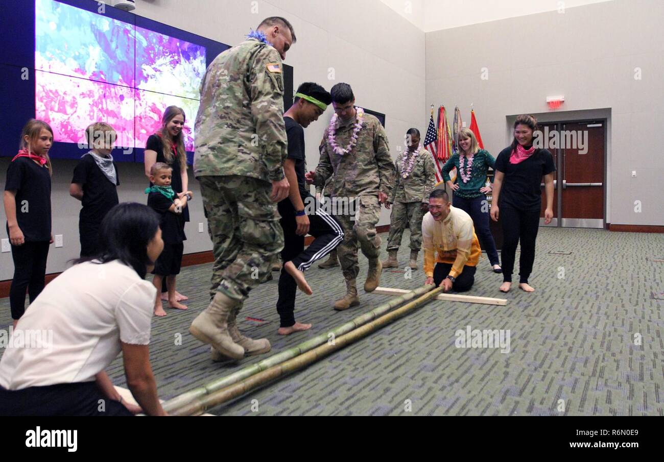 Plusieurs enfants centrale de l'armée américaine pour enseigner la Tinikling USARCENT membres, comme le colonel Roy Banzon, USARCENT inspecteur général commandant, et Marlyn Banzon, l'épouse de Banzon, frapper et touchez le perches en bambou en rythme de la musique pendant l'USARCENT respect pour la cuisine asiatique et des îles du Pacifique au Mois du patrimoine Hall Patton Le 24 mai. Banque D'Images