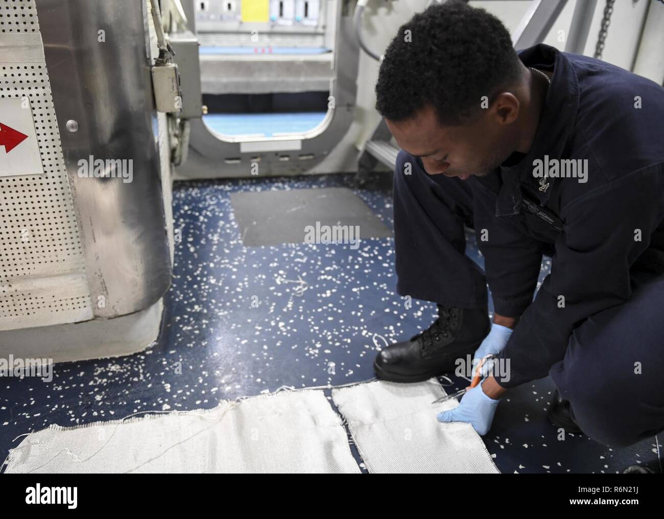 Pacifique occidental (31 mai 2017) Spécialiste des opérations 2e classe Avery Griffin, de Newark, Delaware, coupe un morceau de tissu de verre lors de l'entretien en retard à bord de la classe Arleigh Burke destroyer lance-missiles USS Wayne E. Meyer (DDG 108). La Marine américaine a patrouillé les Indo-Asia régulièrement du Pacifique pendant plus de 70 ans la promotion de la paix et la sécurité régionales. Banque D'Images