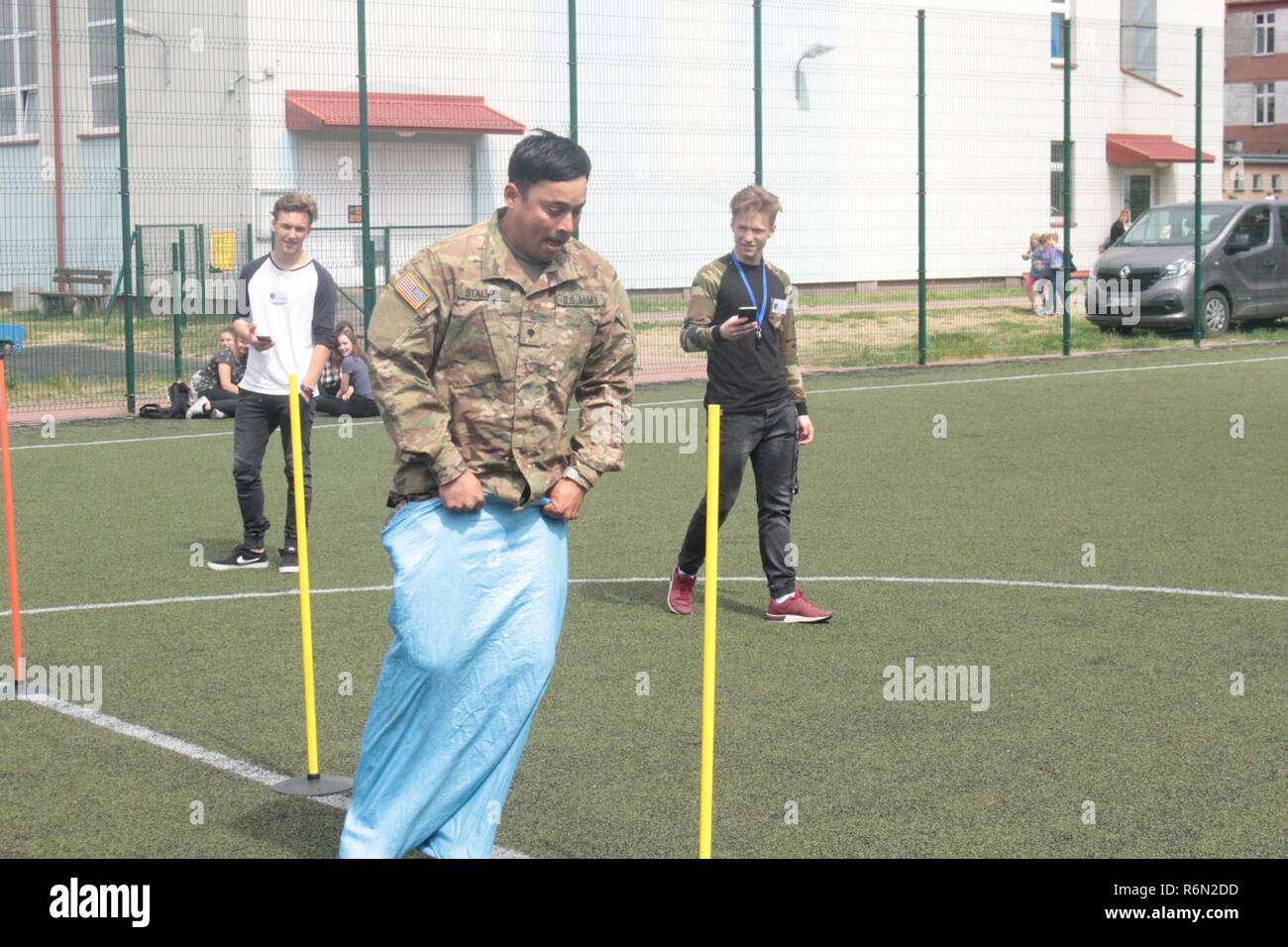 Pologne Groupe de combat des soldats américains en concurrence dans un sac course avec les élèves d'une école locale de Wydminy, la Pologne au cours de l'OTAN de l'école Jours de l'événement le 30 mai . Le groupement tactique est en Pologne dans le cadre de l'OTAN et de la présence accrue de l'avant les États-Unis, le Royaume-Uni et les soldats roumains de l'unité multinationale ont été très actif avec les communautés voisines tout comme un moyen de rendre les citoyens conscients de leur présence et d'en apprendre davantage sur la mission du groupe de combat. Banque D'Images