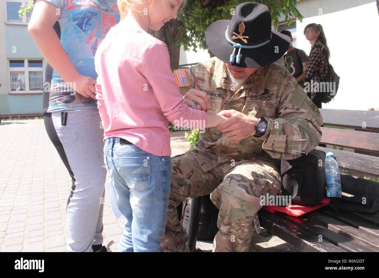 Pologne Groupe de combat de sergent-major de commandement Joe Chadwick, signe des autographes pour les étudiants d'une école locale de Wydminy, la Pologne au cours de l'OTAN de l'école Jours de l'événement le 30 mai . Le groupement tactique est en Pologne dans le cadre de l'OTAN et de la présence accrue de l'avant les États-Unis, le Royaume-Uni et les soldats roumains de l'unité multinationale ont été très actif avec les communautés voisines tout comme un moyen de rendre les citoyens conscients de leur présence et d'en apprendre davantage sur la mission du groupe de combat. Banque D'Images