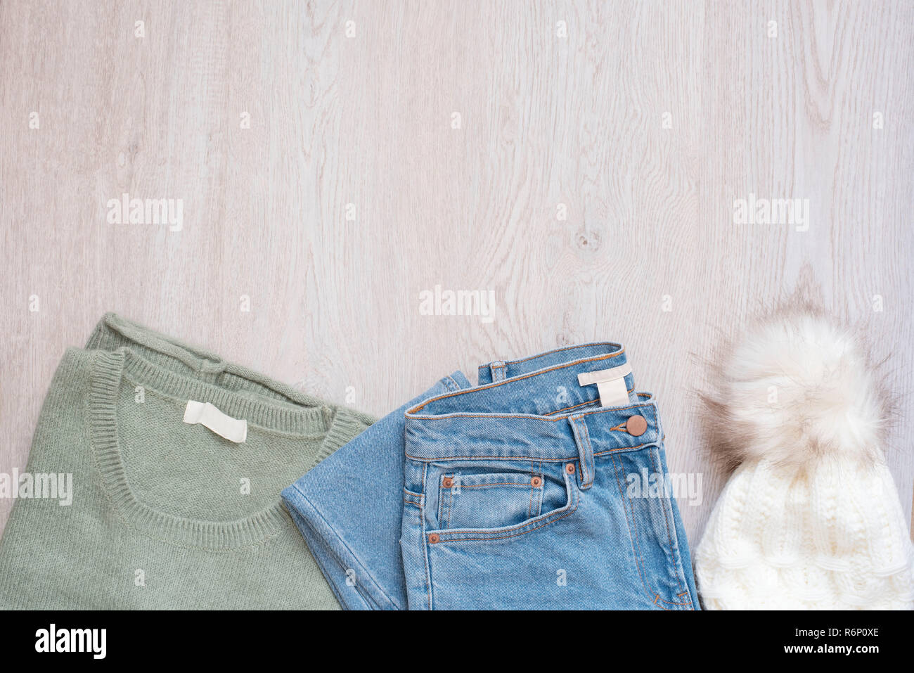 Vêtements Mode femmes sur fond de bois. Mise à plat de style féminin. Pull, jeans et chapeau de fourrure. Vue d'en haut. Concept commercial. Jeu de mode tenues Banque D'Images