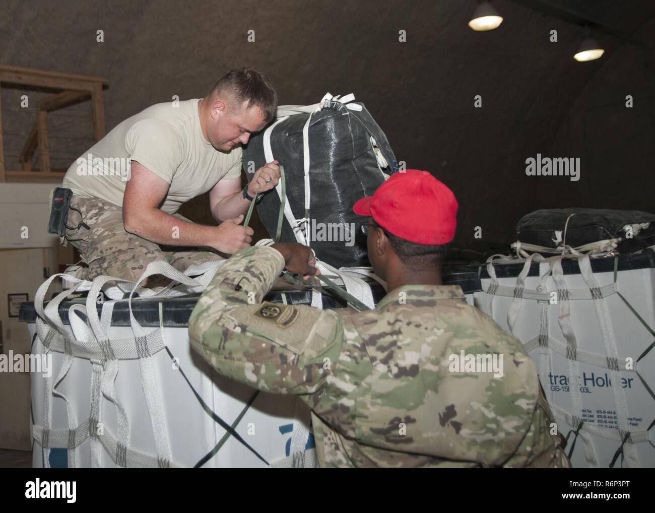 La CPS. Alexander Triska et SPC. Keith Manning du 824ème Compagnie de quartier-maître, fixer un parachute à un récipient pour la livraison aérienne à Al Udeid Air Base, au Qatar le 25 avril 2017. Les opérations de livraison aérienne sont essentiels pour obtenir les troupes au Moyen-Orient, lorsque les moyens de transport ne sont pas possibles. Banque D'Images