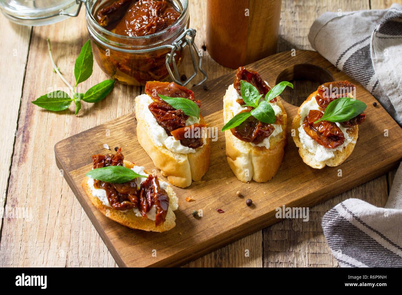 Antipasti italiens des en-cas pour le vin. Brushetta avec fromage doux et tomates séchées sur une table en bois. Banque D'Images