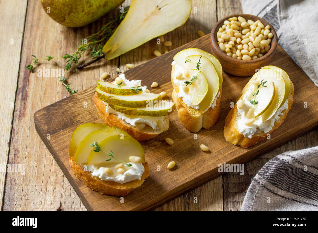 Antipasti italiens des en-cas pour le vin. Brushetta avec fromage, poire et noix de pin sur une table en bois. Banque D'Images