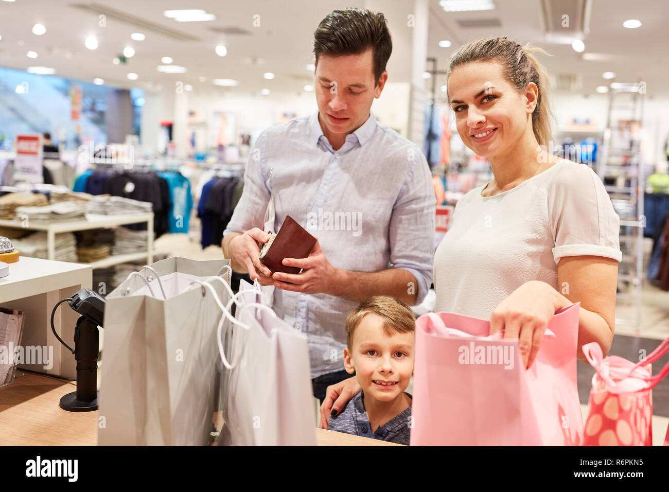 Famille avec enfant payé comptant à la caisse à la mode en magasin shopping mall Banque D'Images