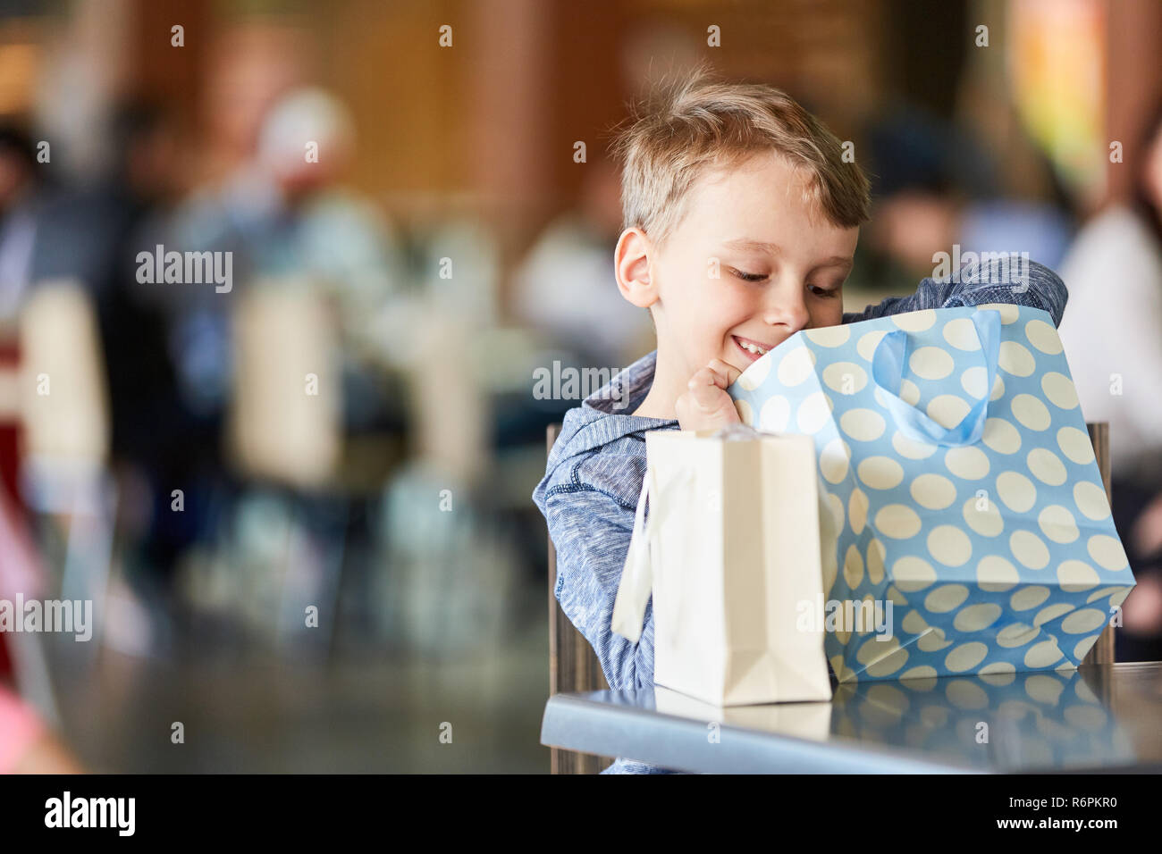 Garçon ressemble curieusement dans un sac d'épicerie et attend avec intérêt son présent Banque D'Images