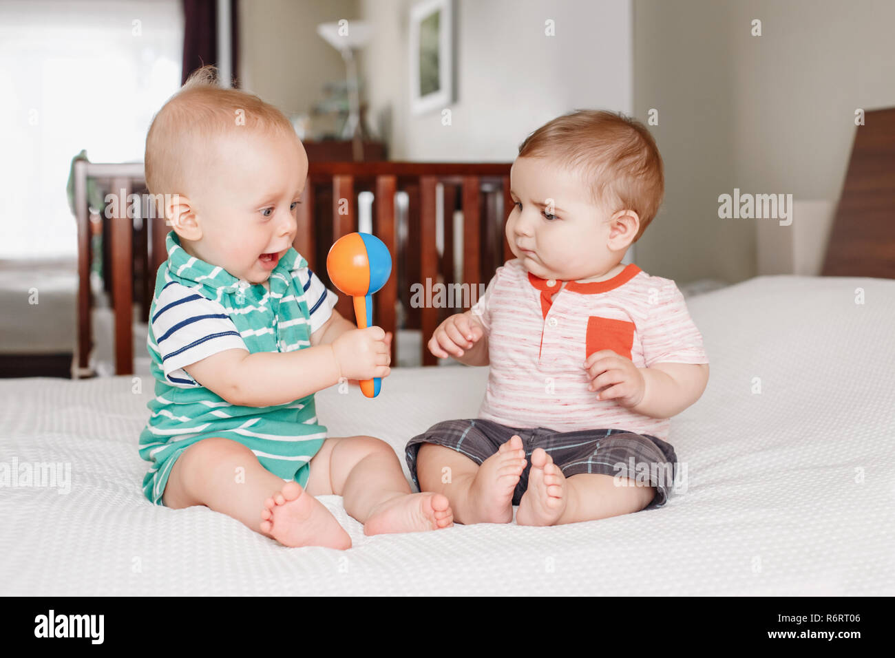 Portrait de groupe de deux white Caucasian cute funny baby garçons assis ensemble sur le partage du lit jouet. Concept de la petite enfance de l'amitié. Meilleurs amis pour toujours. Ea Banque D'Images