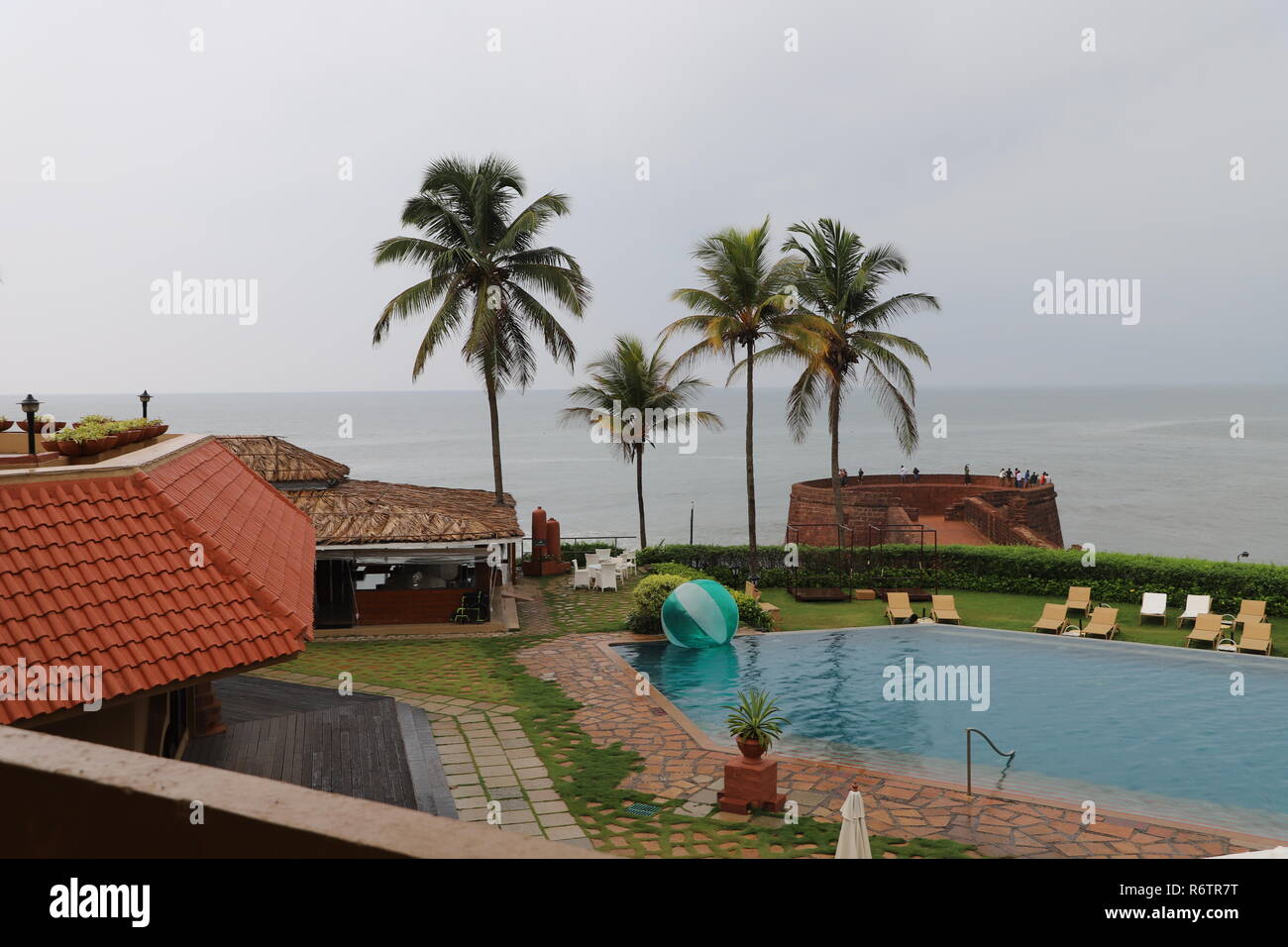 Vue apaisante d'un fort resort dans le Nord de Goa composé d'une piscine extérieure, d'abris, de villégiature exotique cocotiers et la mer sans fin Banque D'Images