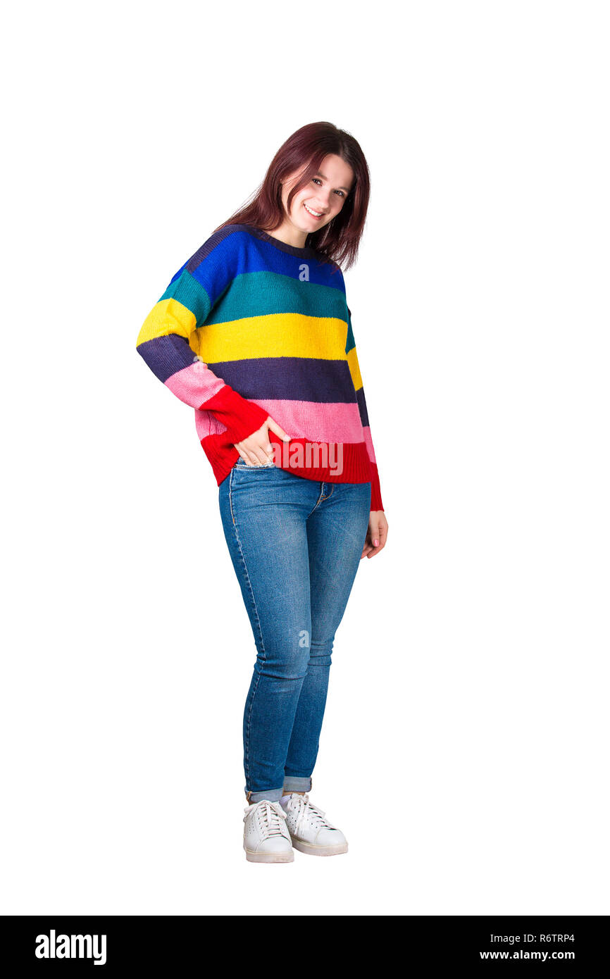 Portrait de casual young woman wearing jeans et pull arc-en-main tenant dans la poche et souriant à l'appareil photo voir plus isolé bac blanc Banque D'Images