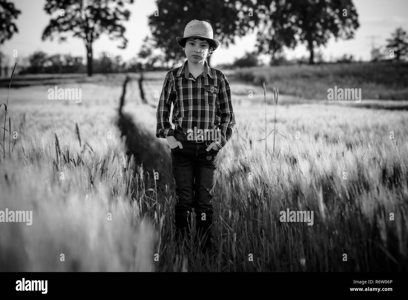 Un garçon en jeans et d'une chemise est debout dans le champ. Noir et blanc. Banque D'Images