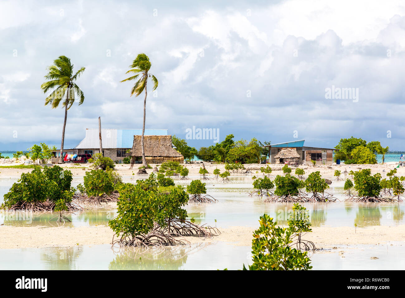 Village sur l'atoll de Tarawa Sud, Kiribati, Micronésie, l'Océanie. Maisons à toit de chaume. La vie rurale sur une plage de Paradise Island à distance sous les palmiers. Banque D'Images