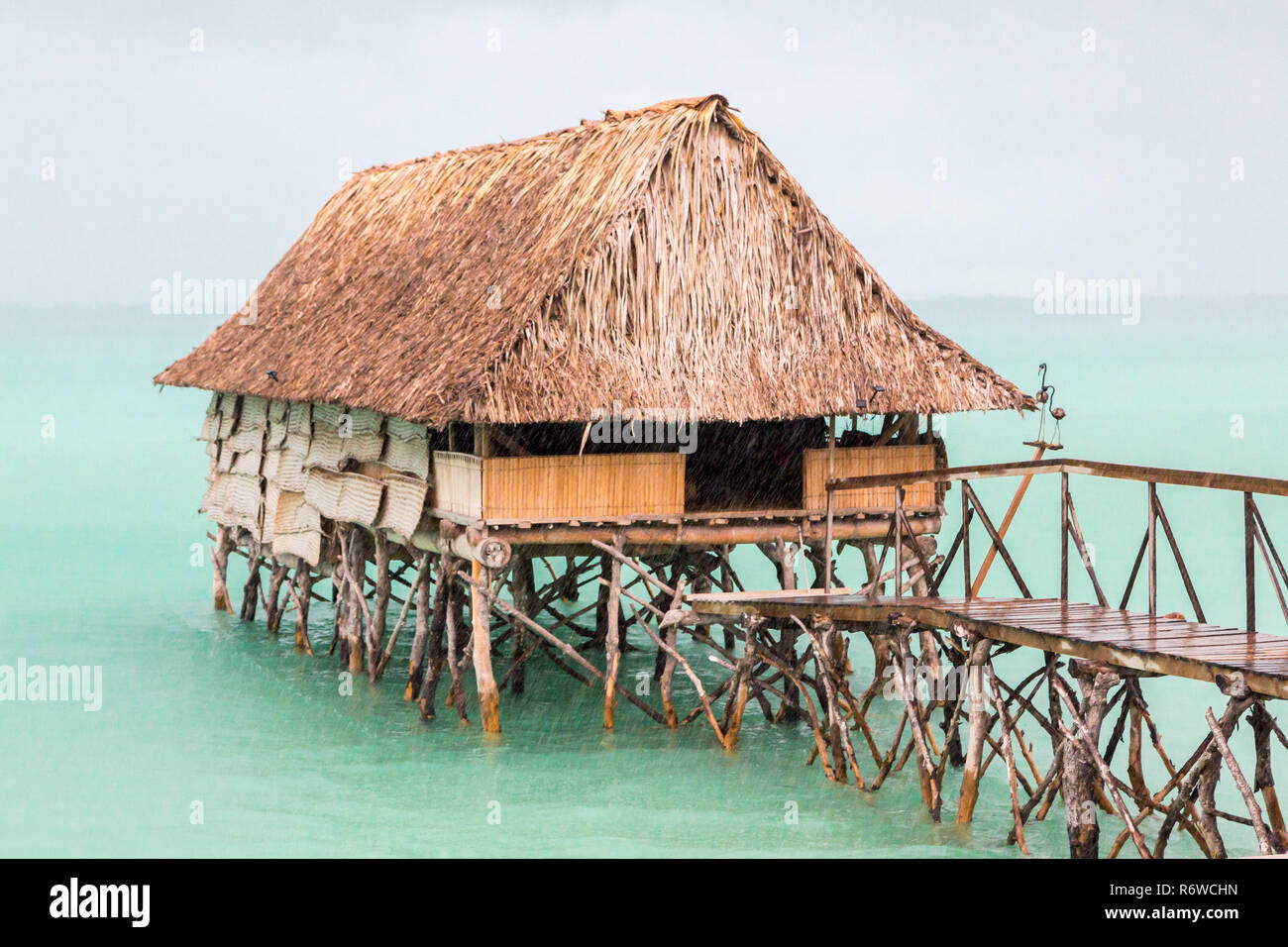 Toit de chaume sur pilotis bungalow cabane de population micronésienne, lagon de Tarawa Sud, forte pluie douche, saison humide, Kiribati, Micronésie, l'Océanie. Banque D'Images
