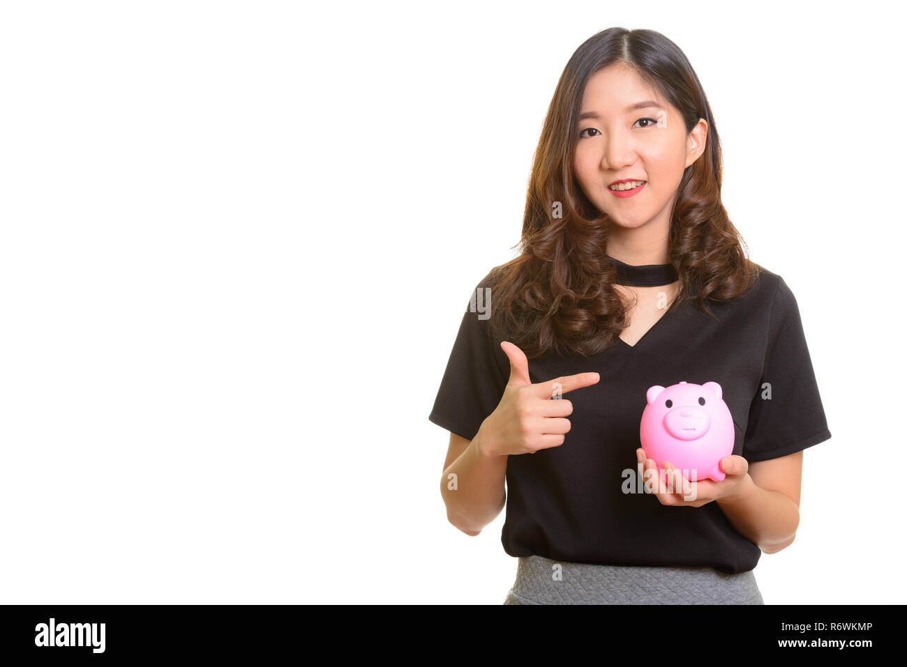 Young happy Asian businesswoman holding Piggy Bank et de pointage Banque D'Images