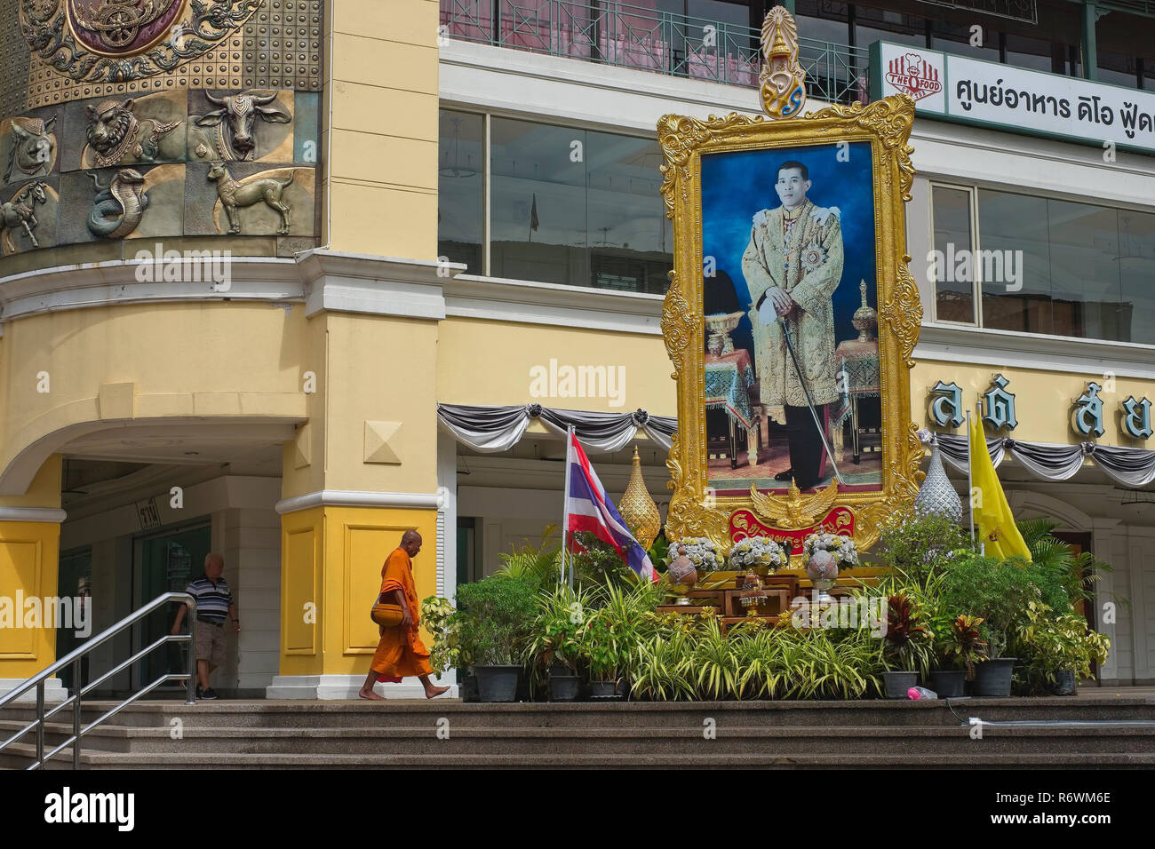 Un moine bouddhiste promenades sous un grand portrait du roi thaïlandais Maha Vajiralongkorn, à l'Old Siam centre commercial en zone Pahurat, Bangkok, Thaïlande Banque D'Images