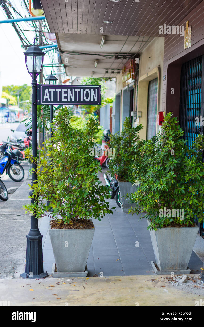 Un signe d'attention de décoration au hasard attaché à un lampadaire sur un trottoir de la ville. Banque D'Images