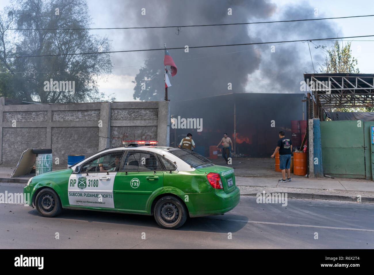 Voiture de police s'arrêta devant un feu à l'intérieur d'un atelier dans le quartier Pudahuel à Santiago du Chili en ville entre la fumée Banque D'Images