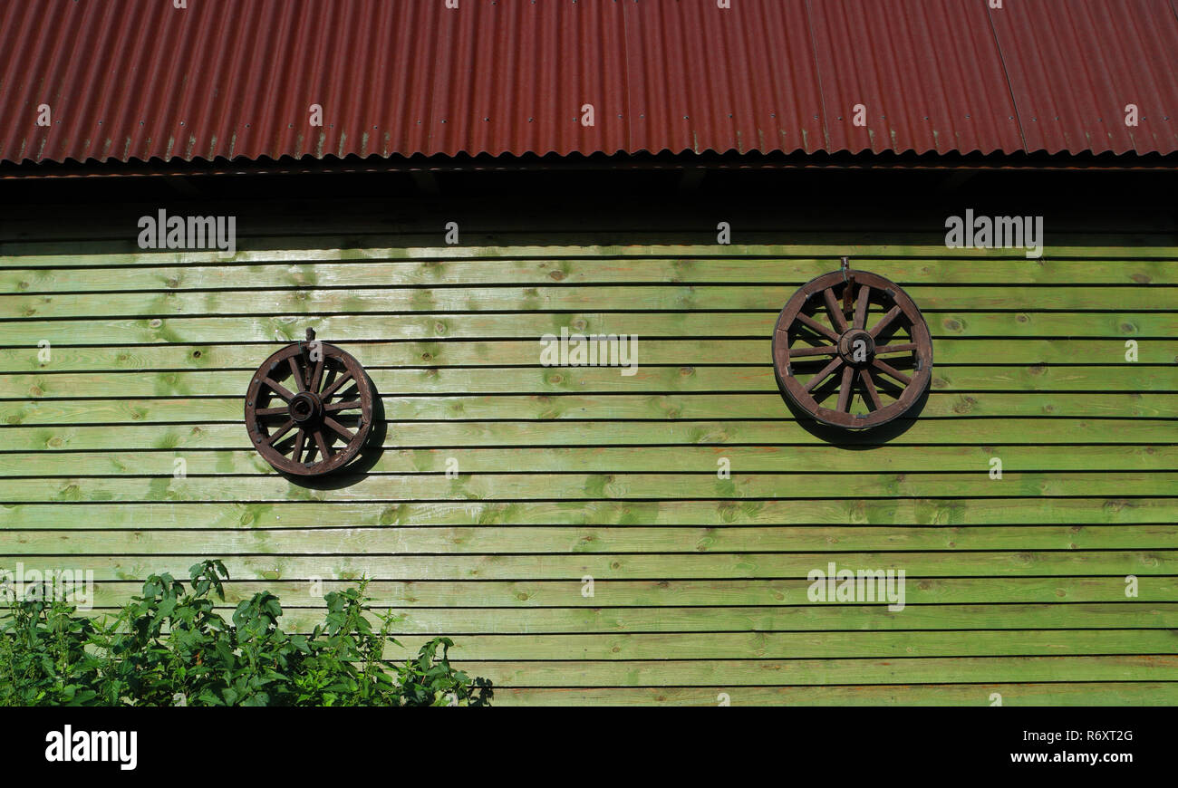 Deux anciennes roues en bois sur mur de maison en bois Banque D'Images